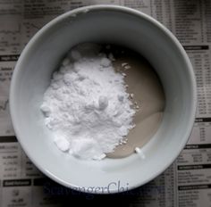 a bowl filled with white powder on top of a newspaper