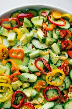 cucumber salad with peppers and onions in a white bowl on top of a table