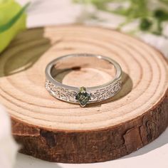 a close up of a ring on a piece of wood with flowers in the background