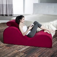 a woman sitting on a bean bag chair reading a book in a room with hardwood floors