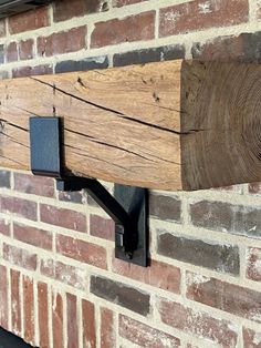 a piece of wood is mounted to the side of a brick wall with metal brackets