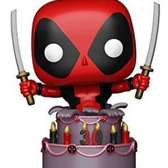 deadpool pop vinyl figure on top of a birthday cake with candles and two swords