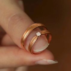 a woman's hand holding a ring with a diamond on it and the middle finger