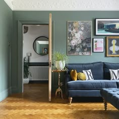 a living room with blue couches and pictures on the wall above them, along with wooden flooring