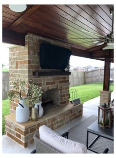 an outdoor living area with furniture and a television on the fireplace in the back yard