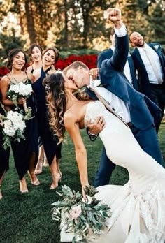 a bride and groom kissing in front of their wedding party