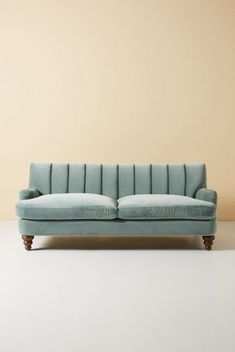 a blue couch sitting on top of a white floor next to a brown and tan wall