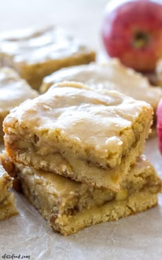 apple pie bars stacked on top of each other next to an apple and another piece of fruit