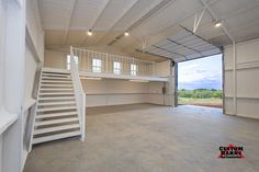 an empty garage with stairs leading up to the second floor and open doors on both sides