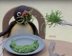 a small penguin sitting at a table with a plate and fork in front of it