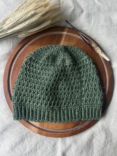 a green knitted hat sitting on top of a wooden plate