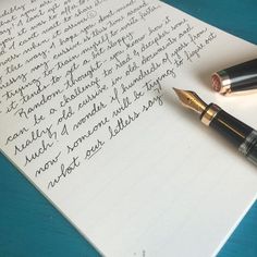 two fountain pens sitting on top of a piece of paper next to an ink pen