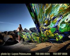 a woman standing on top of a rocky beach next to a large piece of art