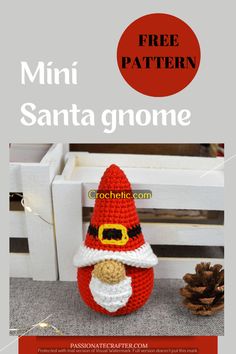 a crocheted santa gnome sitting next to a pine cone