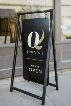 a sign that says boutique we are open on the sidewalk