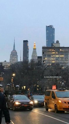 a busy city street with lots of traffic and tall buildings in the background at dusk