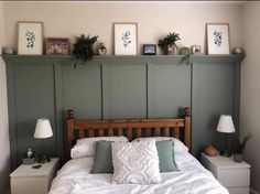 a bed with white sheets and pillows in a bedroom next to two framed pictures on the wall