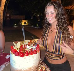 a woman sitting in front of a cake with strawberries on it