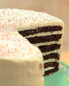 a cake with white frosting and red sprinkles on top is sitting on a green plate