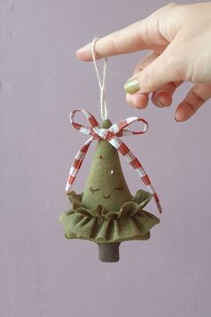 a hand holding a christmas ornament in the shape of a tree with a green dress on it