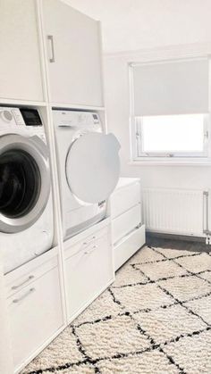 a washer and dryer in a small room with white cabinets on the walls