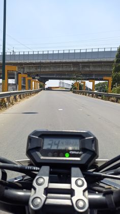 the handlebars on a motorcycle are visible as it travels down an empty road