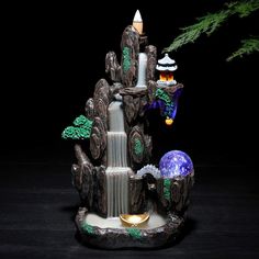 a small fountain with lights and decorations on the top in front of a black background