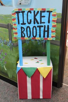 a cardboard circus ticket booth sitting in front of a wall with a sign that says ticket booth