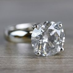 an oval cut diamond sits on top of a wooden table, with the center stone missing