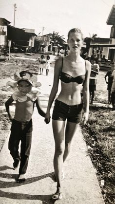 an old photo of a woman and child walking down the street holding hands with each other