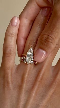 a woman's hand holding an engagement ring with two pear shaped diamonds on it