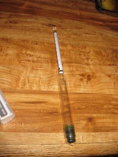 an empty glass bottle sitting on top of a wooden table next to a toothbrush