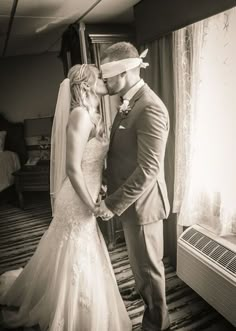 a bride and groom standing in front of a window