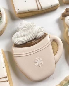 some cookies and cupcakes are arranged on a table top with frosting in the shape of mugs