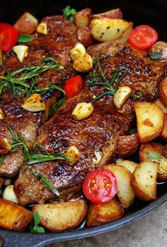 a pan filled with meat, potatoes and tomatoes