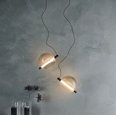 two light fixtures hanging from the ceiling in a room with concrete walls and flooring