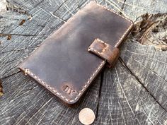 a brown leather wallet sitting on top of a tree stump next to a penny coin