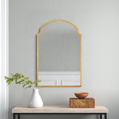 a table with a vase and mirror on it in front of a wall mounted mirror