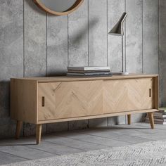 a wooden sideboard with a mirror on the wall and books in front of it