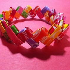 a close up of a candy bracelet on a pink surface