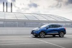 a blue car parked in a parking lot next to a building with a glass roof