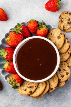 chocolate sauce in a bowl surrounded by cookies and strawberries