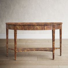 an old wooden table sitting on top of a hard wood floor next to a white wall