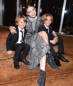 a woman and two boys sitting on the ground