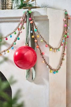 a red balloon hanging from the side of a white wall next to a christmas tree