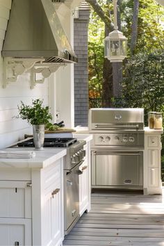 an outdoor kitchen with white cabinets and stainless steel appliances