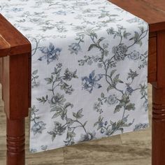 a wooden table with a white and blue floral design on the table cloth over it