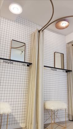 the interior of a bathroom with white tiled walls and floor, along with two stools