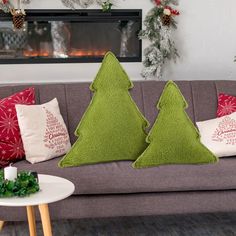 two green christmas trees sitting on top of a couch in front of a fire place