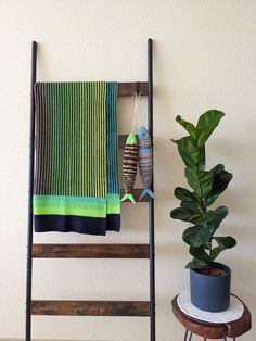 a towel rack and potted plant in front of a wall hanging on the wall